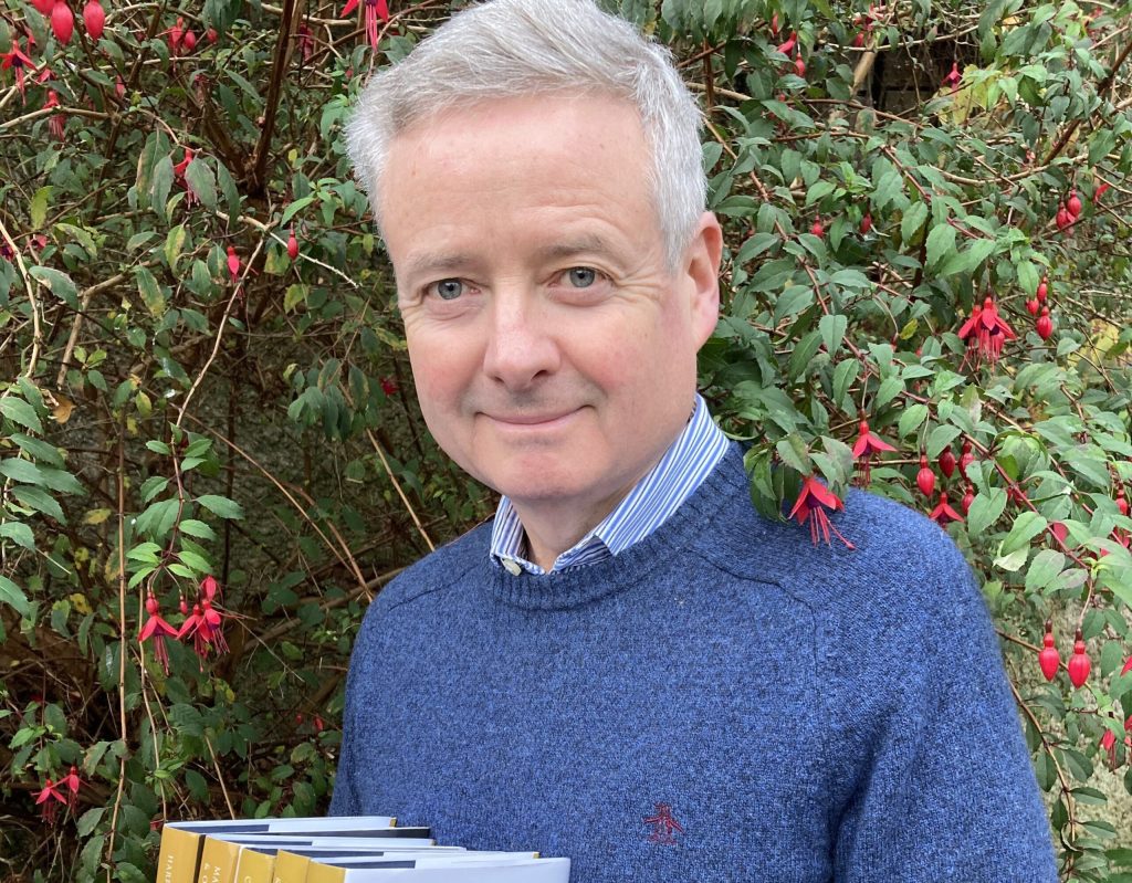 Professor John McCafferty standing in front of a hedge